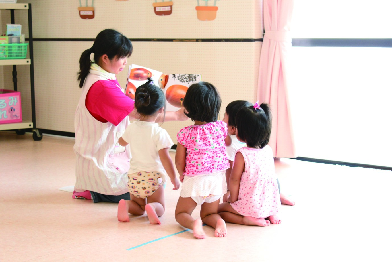 読み聞かせをする保育者と子どもたち