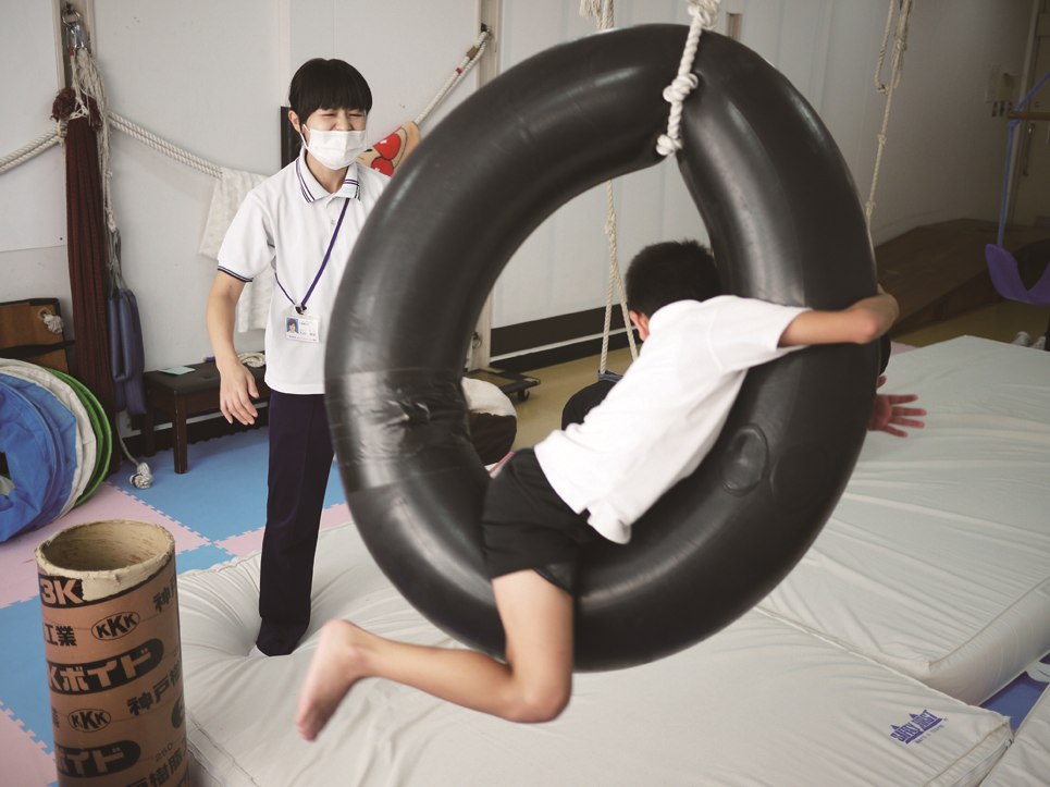 スタッフが付き添い、吊り遊具を使っている訓練の様子
