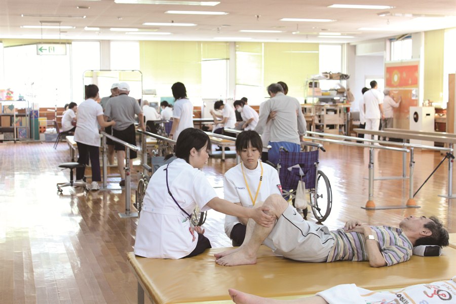 スタッフと患者様がリハビリ室で訓練する様子